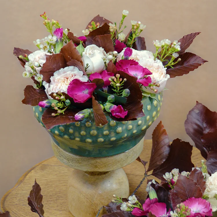 fleurs rose et bordeaux dans coupe bouquet violet et jaune